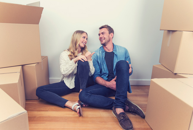 Couple sitting on floor surrounded by moving boxes