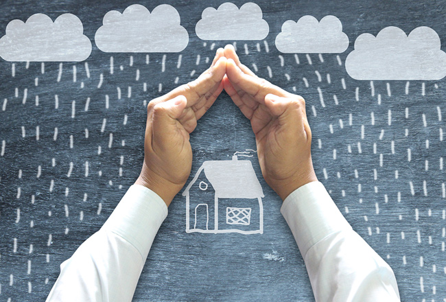 Hands shielding roof of illustrated house from rain