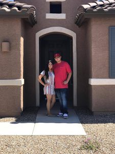 Couple standing in front of front door of their home