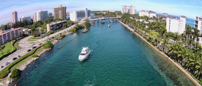 Boat driving through channel surrounded by palm trees and large resort buildings