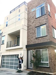 Woman jumping for joy in front of entry to her new home