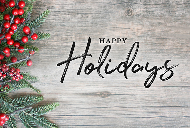 The words 'Happy Holidays' over wood background with decorative greenery