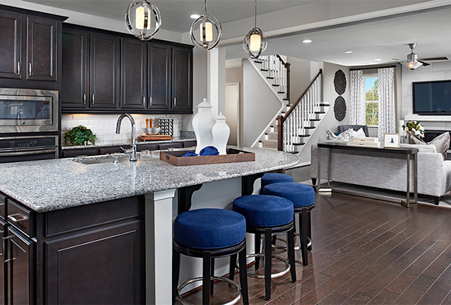 Kitchen with dark cabinets, light countertops and blue barstools