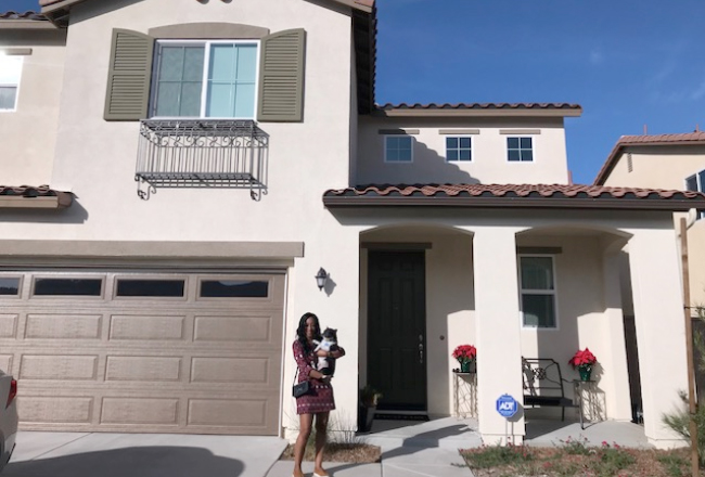 Woman poses in front of her new home