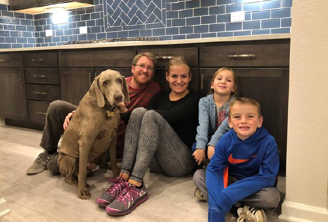 Family of four and dog sitting on kitchen floor