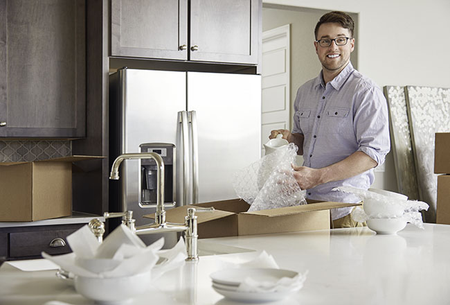 Man boxing up dishes in kitchen