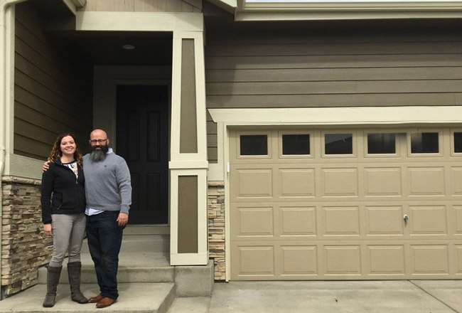 Couple standing in front of covered entry of new home