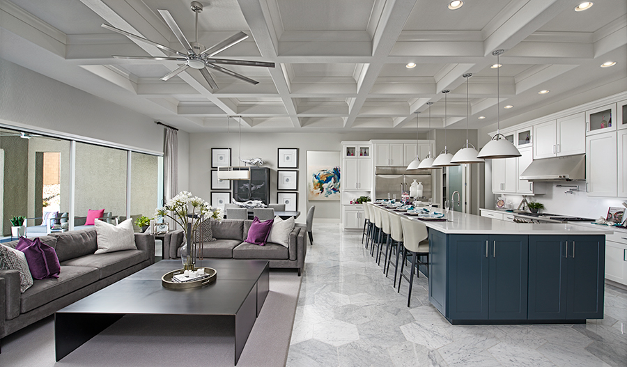 Great room and kitchen with coffered ceiling, hexagonal tile flooring and white pendants and ceiling fan