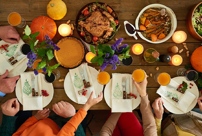 People sitting at table with Thanksgiving place settings and meal