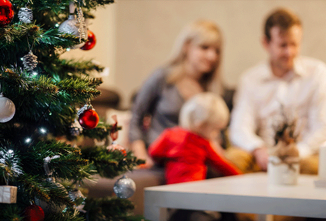 Christmas tree with family of three in background