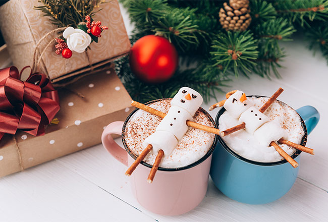 Two marshmallow snowmen on top of mugs of hot cocoa