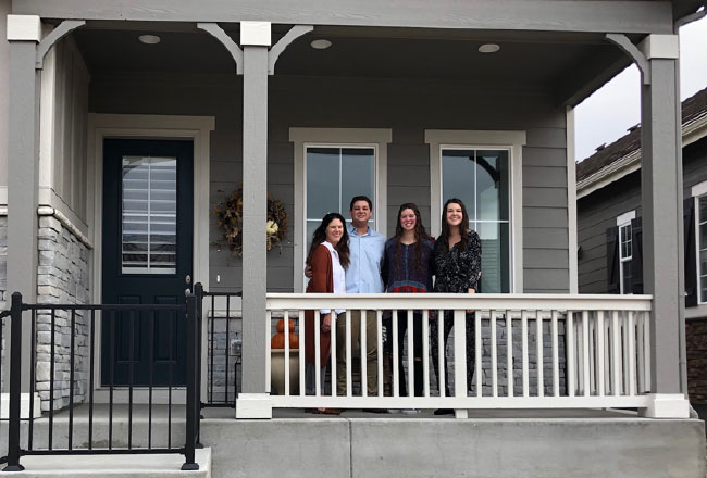 Family of four standing on front porch
