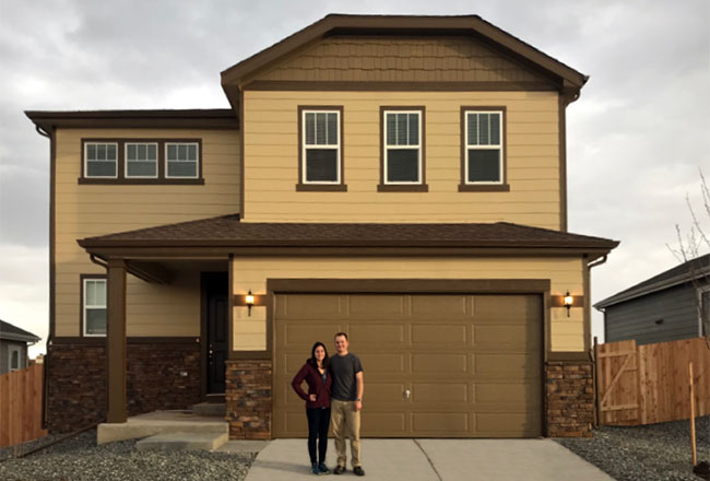 Couple standing in front of their new two-story home