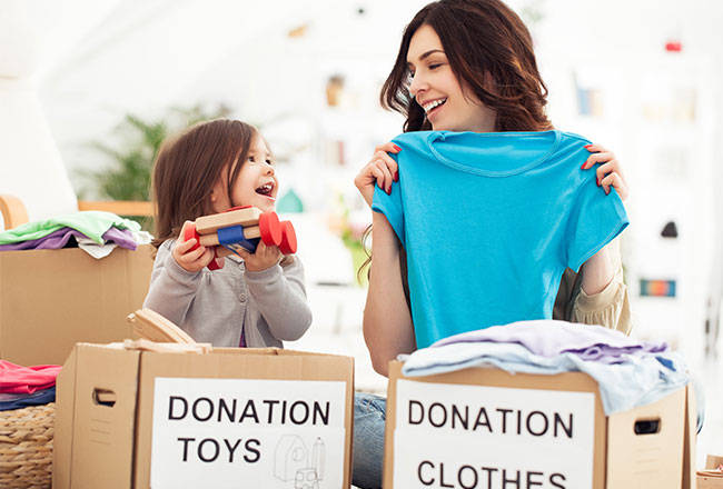 Mother and daughter putting toys and clothes in donation boxes