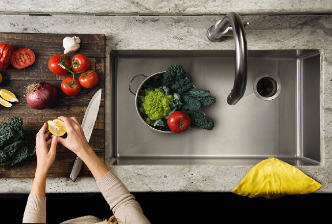 Women washing vegetables in stainless-steel sink