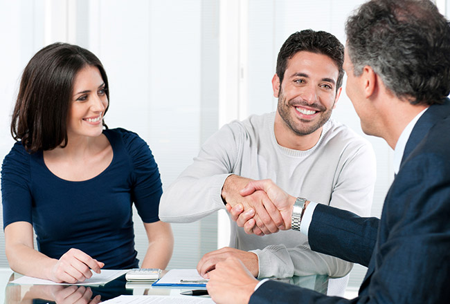 Two men shaking hands while woman watches