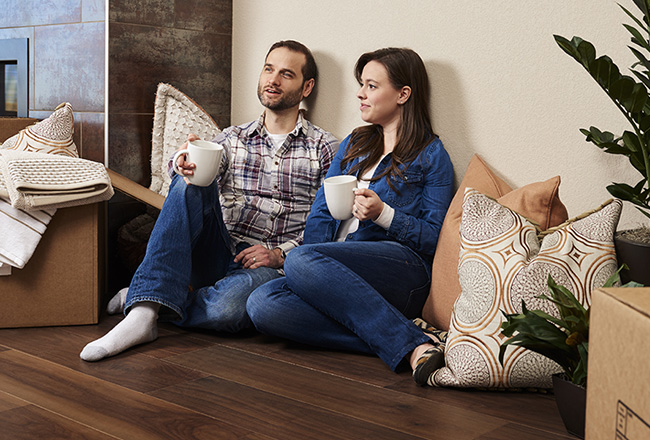Couple sitting on floor drinking coffee while unpacking