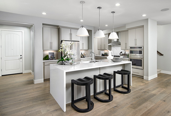 Kitchen with dark stools and white cabinets, island and light fixtures 