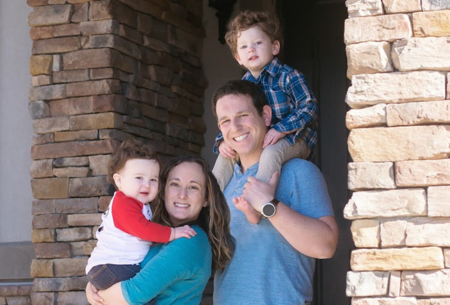 Family of four standing in covered entry to their home