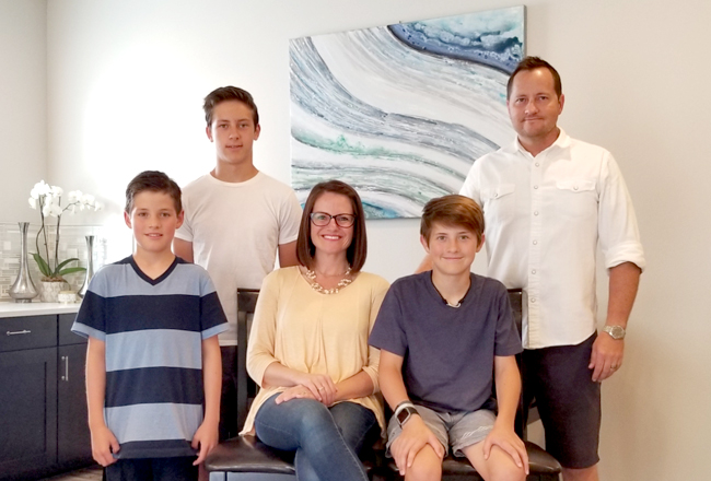 Family of five standing in front of painting inside their home