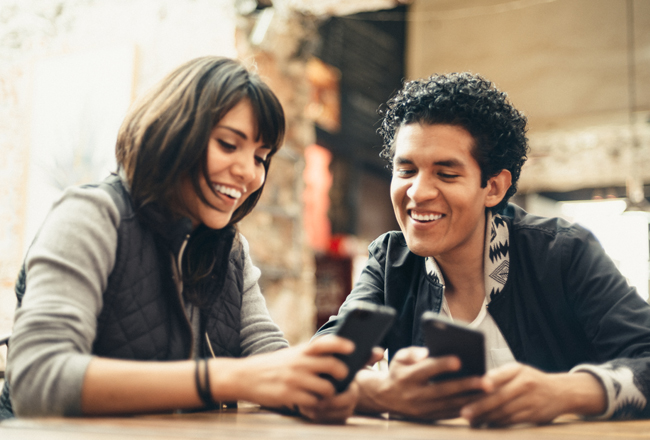 Smiling couple looking at their cell phones