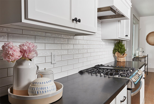 Kitchen with black natural stone counters, white cabinets and white subway tile backsplash