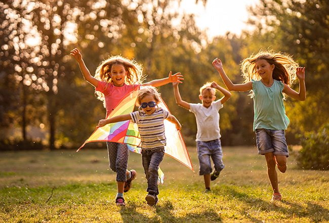 Children running with kite in yard