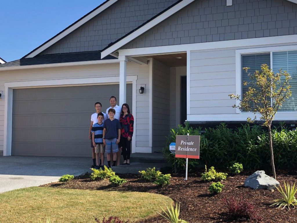 Family of five standing in front of their home