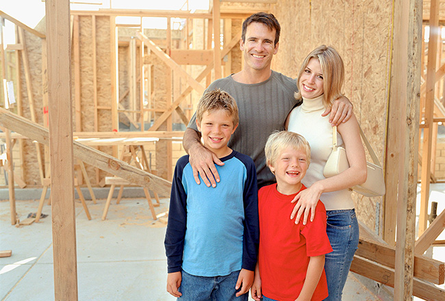 Family of four standing inside of home that is under construction