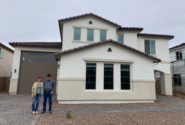 Couple standing in driveway of two-story home with attached RV garage