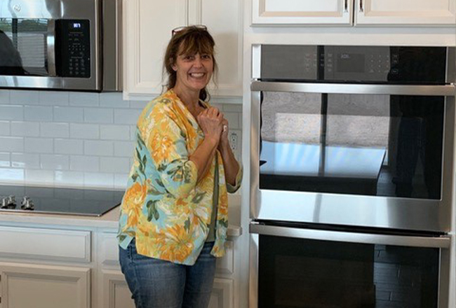 Woman standing next to a stainless-steel double wall oven