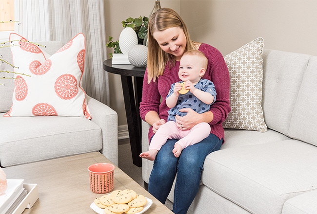 Mother sitting with baby on her lap as baby eats a cookie