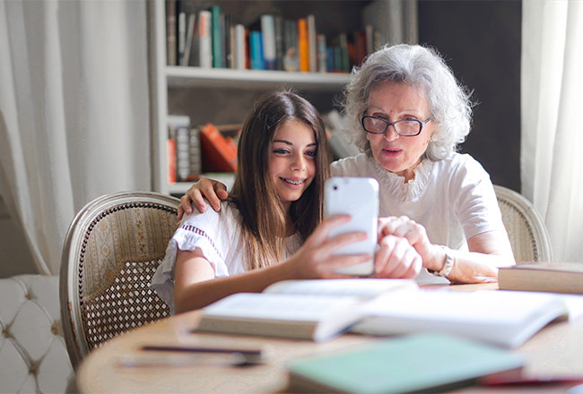 Woman and young girl looking at cell phone while seated at table