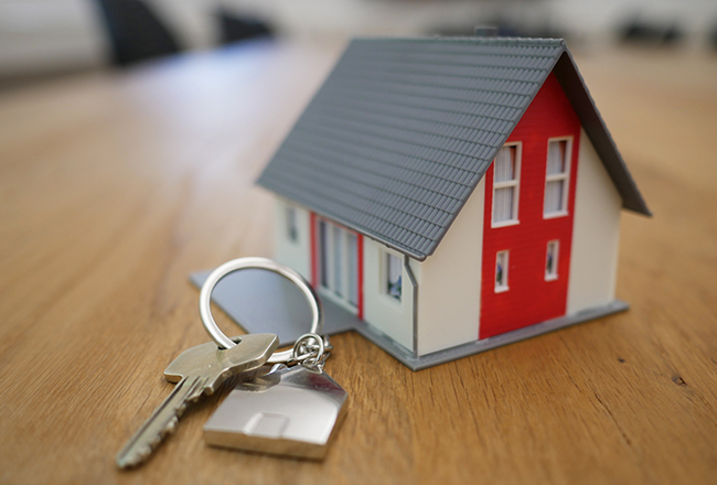 House key sitting on table next to miniature home