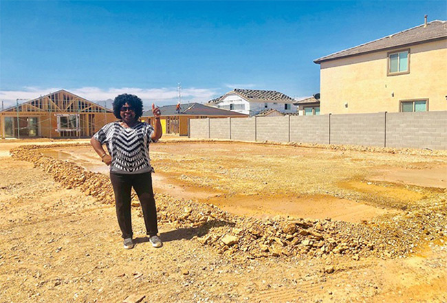 Woman standing on dirt lot where house will be built