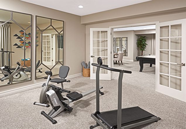 Home gym with large mirrors, workout equipment, and French doors leading to game room
