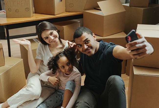 Family of three surrounded by moving boxes