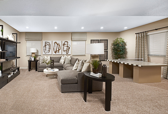 Living room with sectional facing television and shelves and ping pong table behind it.