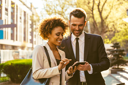 Two people in suits looking at a phone