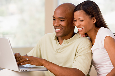 Couple smiling while typing on laptop