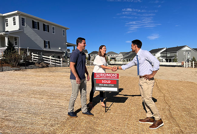 Couple shaking hands with Sales associate in empty lot