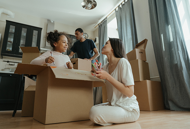 Parents and young daughter packing moving boxes in a kitchen