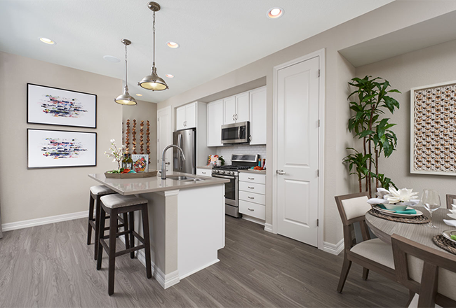 Kitchen with island with two chairs, pantry, white cabinets, and stainless steel appliances