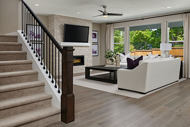 Stairs with traditional railings overlooking a great room with a fireplace