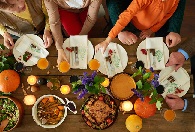 People sitting at table with Thanksgiving place settings and meal