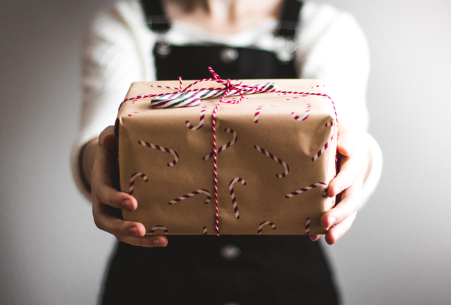 Woman holding gift wrapped in holiday wrapping paper