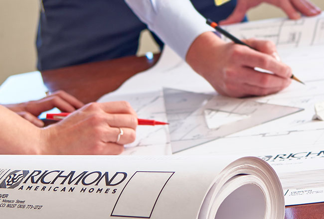 Hand drawing on blueprints laid out on a table