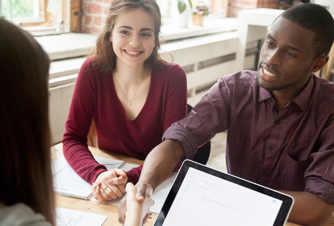 Couple sitting at table with agent and paperwork