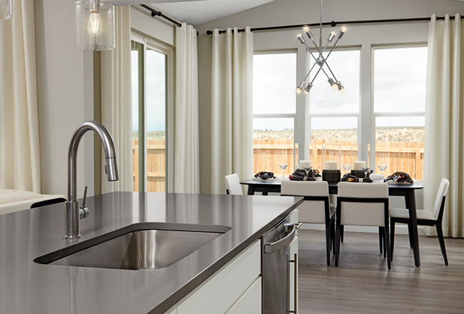 Kitchen with modern nickel faucet and adjoining dining room with modern pendant