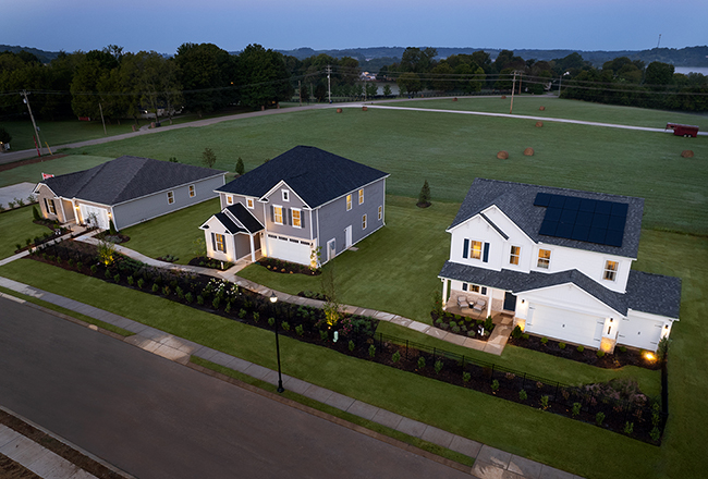 Aerial view of three homes, showing the large backyard space. The house on the left is single story, and the middle and right homes are two story homes